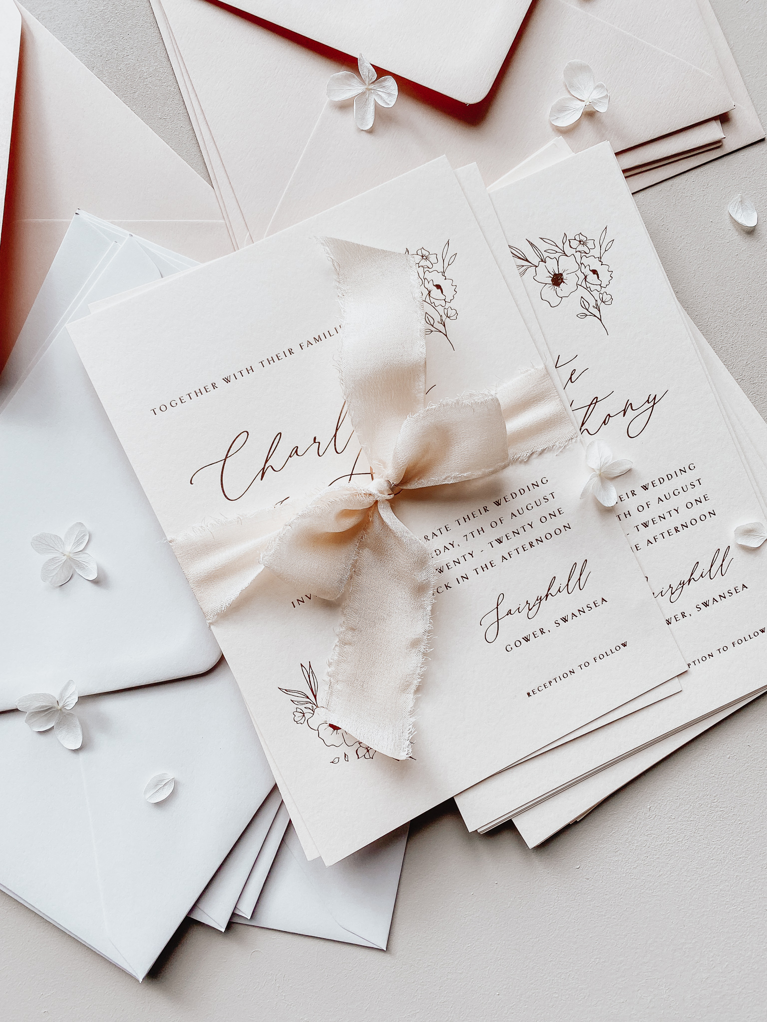 Rose gold hot foil press wedding invitations on nude blush card, finished with silk ribbon.