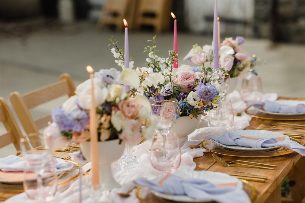 Styled wedding table with pastel toned flowers, candles and place settings.